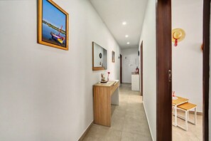 A hallway with a wooden desk, a framed painting, and a door with a straw hat decoration. - Holiday Home 'A Casa Da Velha' with Private Terrace, Wi-Fi and Air Conditioning (Alvor)