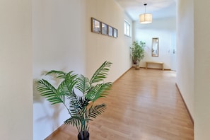 Ein Flur mit Holzboden, einem Blumentopf, einer Bank und gerahmten Bildern an der Wand.