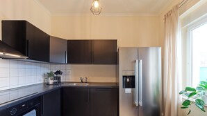 A modern kitchen with dark cabinetry, a stainless steel refrigerator, a built-in oven, and a sink. - Spacious Central Apartment for 6 Guests in the Heart of Trier (Trier)