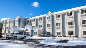 Un hotel de varios pisos con estacionamiento y suelo cubierto de nieve.