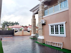 A building with a gated entrance, a covered walkway, and a window with a white frame.