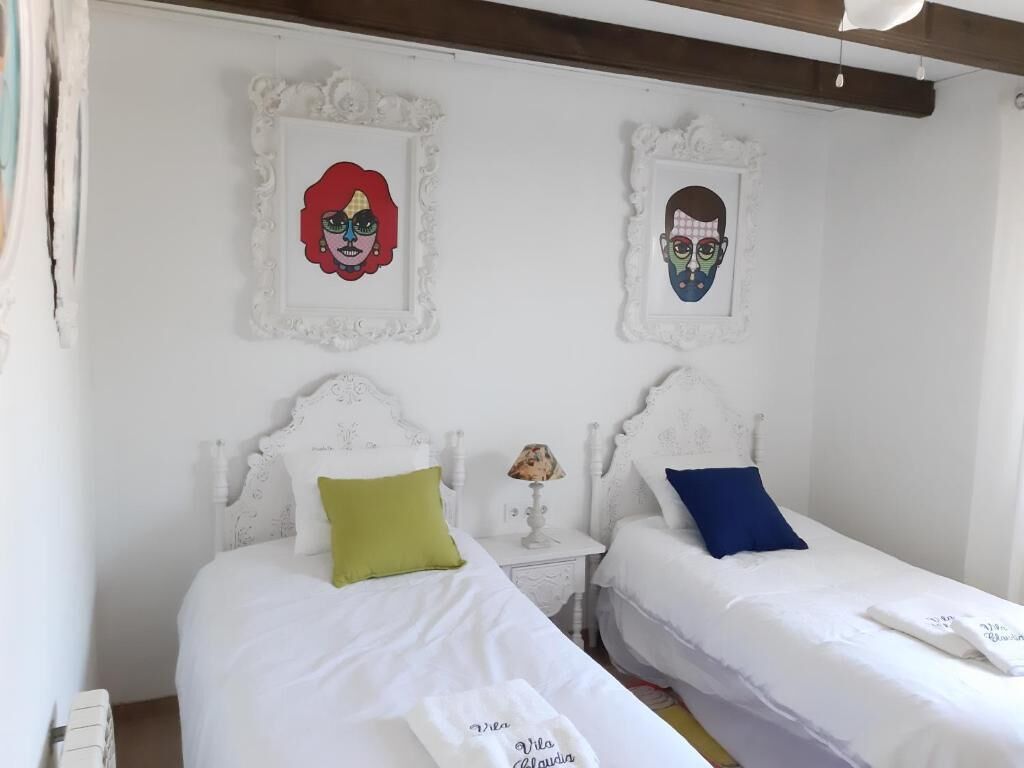 A bedroom with two beds, white bedding, and decorative wall art.