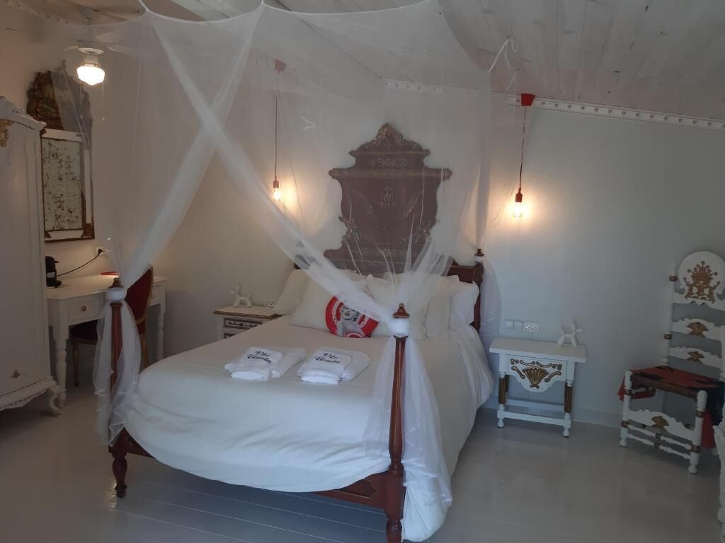 Ein Schlafzimmer mit einem Himmelbett, weißer Bettwäsche, einem Nachttisch und einem Beistelltisch.