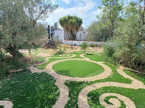 Un jardín con diseños circulares, una estatua y un árbol.