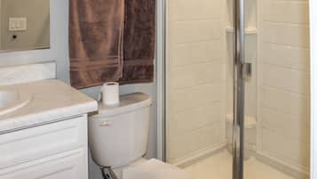 Une salle de bain avec des toilettes, un lavabo, une douche et une serviette accrochée au mur.