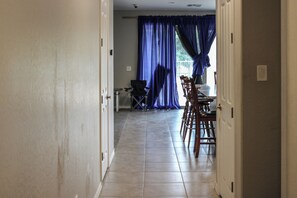 Corredor que leva a uma área de refeições com cadeiras e uma mesa.