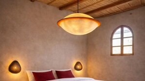 Un dormitorio con una cama plataforma de madera, dos lámparas fijas en la pared y un ventanal con vistas.