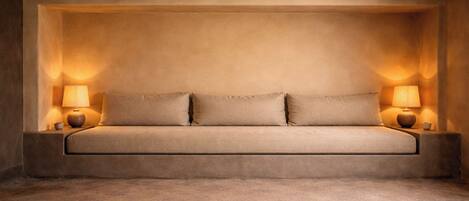 A room with a sofa bed, two bedside lamps, and a textured ceiling.
