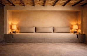 Quarto com sofá-cama, duas luminárias de cabeceira e teto texturizado.