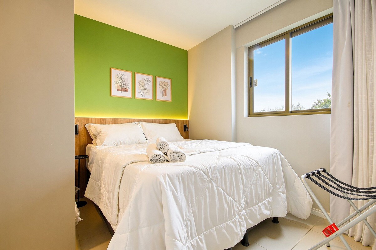 Ein Hotelzimmer mit einem Bett, einem Fenster und einer Wand mit drei gerahmten Bildern.