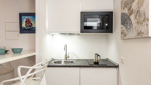 Een kleine keuken met een RVS spoelbak, een waterkoker en een magnetron.