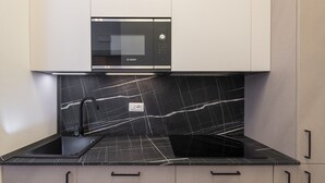 Eine Küche mit einem eingebauten Bosch-Mikrowellenherd, einer schwarzen Marmor-Spritzschutzwand und einer schwarzen Arbeitsplatte.