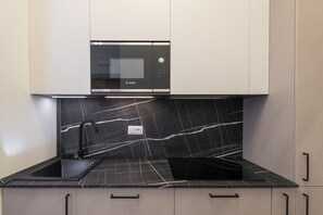A kitchen with a built-in Bosch microwave, black marble backsplash, and a black countertop. - San Francesco Ripa 2 - Fornarina Oasis Cottage (Rome)