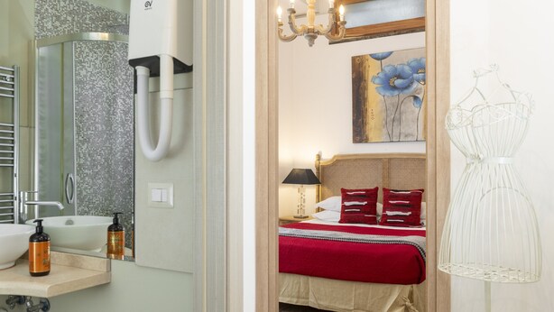 Ein Hotelzimmer mit Bad, einem Bett mit roter Bettdecke, einem Gemälde und einer Kristallleuchter.