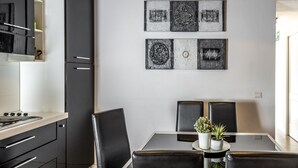 A modern kitchen with black cabinets, a stainless steel range hood, and a dining area with a glass table and black chairs. - San Francesco Ripa 3 - Trilussa 3BR Group & Family Home (Rome)