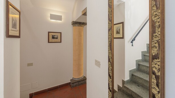 A hallway with a staircase, a column, and framed pictures on the walls. - San Francesco Ripa 3 - Trilussa 3BR Group & Family Home (Rome)