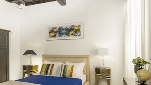 A hotel room with a bed, two bedside tables, a lamp, a globe, and a painting on the wall. - San Francesco Ripa 3 - Trilussa 3BR Group & Family Home (Rome)