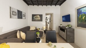 Ein Wohnzimmer mit Sofa, Couchtisch, Fernseher und Kunstwerken an den Wänden.