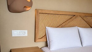 Un dormitorio con cama, una mesita de noche, una lámpara de pared y un enchufe.