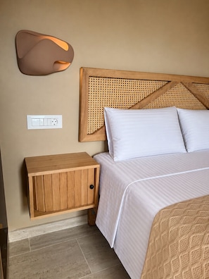 Un dormitorio con una cama, una mesita de noche, una lámpara de pared y un enchufe.