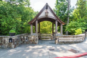 A gazebo with a stone wall and a bench, surrounded by greenery. - Elegant English-Inspired Townhome in Buckhead's Brookwood Hills (Atlanta)