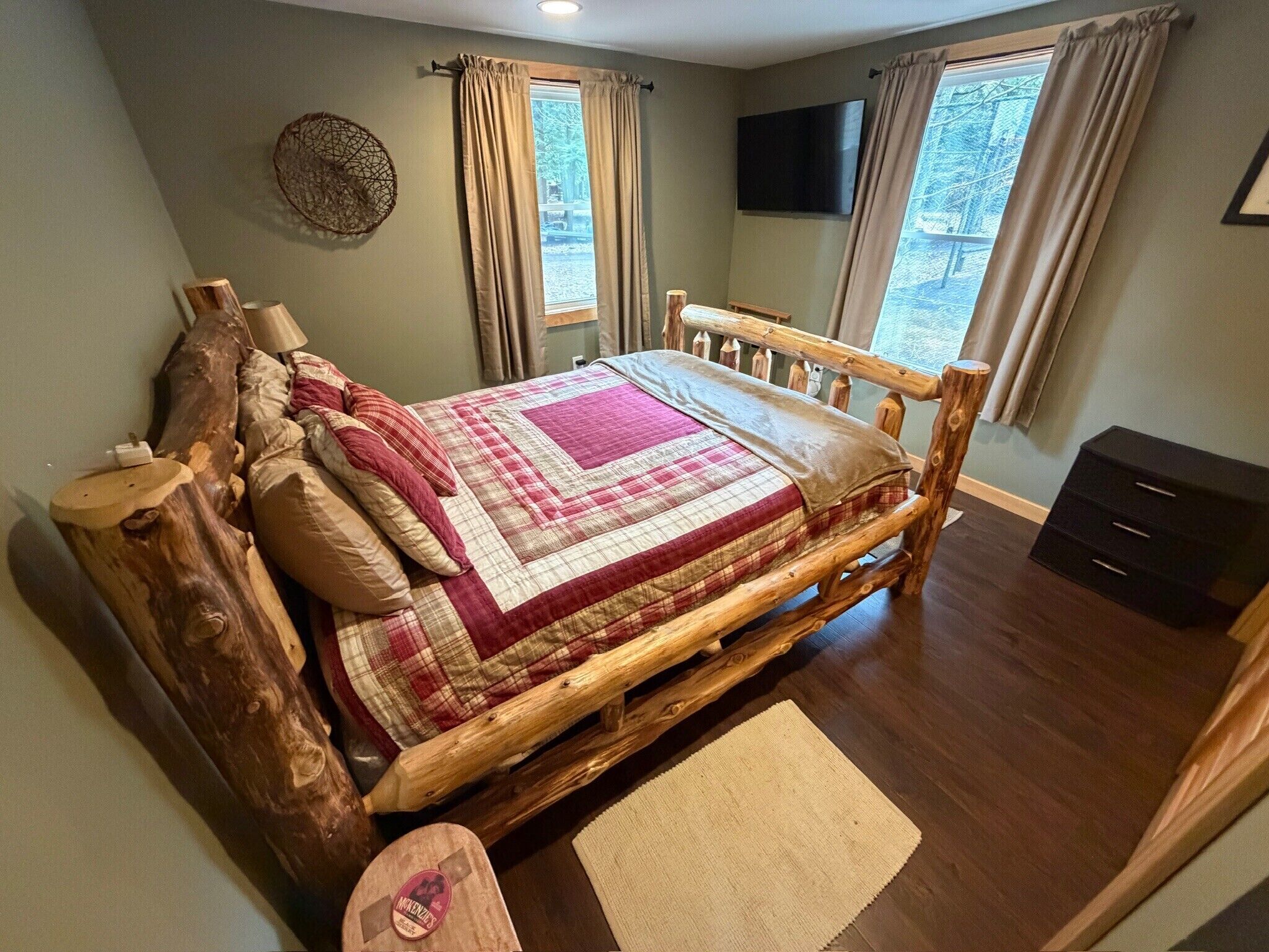 A bedroom with a wooden bed, a television, and a window with curtains.