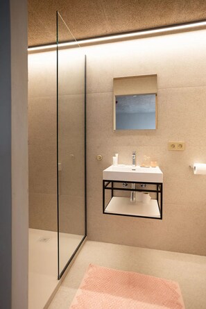 Une salle de bain moderne avec une douche à parois de verre, un lavabo avec un miroir au-dessus et une serviette sur le sol.