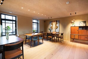 Un espace repas avec des tables et des chaises en bois, une grande fenêtre et un élément décoratif mural.