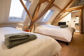 Une chambre avec deux lits, une fenêtre de toit et une vue sur la cuisine.
