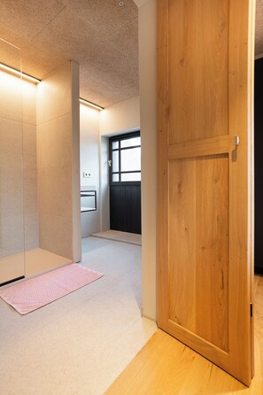 Ein Flur mit Holztür, gefliesten Wänden und einem Fenster mit Jalousien.