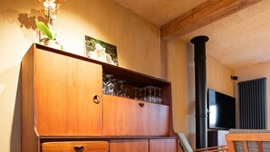 Un meuble en bois avec des tiroirs, un vase de fleurs, une chaise et un téléviseur, le tout dans une pièce dont le sol est recouvert de parquet.
