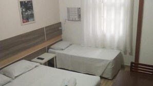 A hotel room with two beds, a wooden headboard, a small table, and a chair. - Hotel Natal de Santos  (Santos)