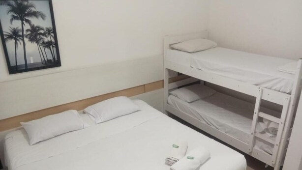 A single bed with white bedding and a lower bunk bed with white bedding. - Hotel Natal de Santos  (Santos)