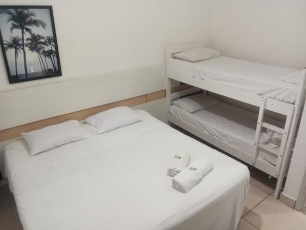 A single bed with white bedding and a lower bunk bed with white bedding.