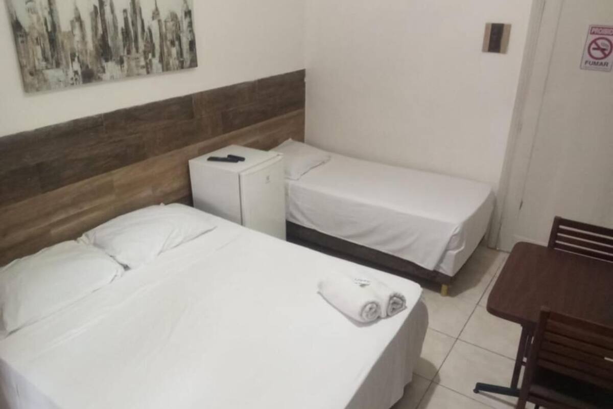 A hotel room with a bed, a small table, and a chair.