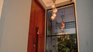 Una puerta de madera, un ventanal y una planta en un pasillo.