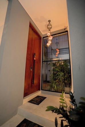Una puerta de madera, un ventanal y una planta en un pasillo.