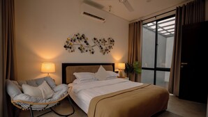 Habitación de hotel con cama, una silla, una obra de arte en la pared y una ventana con cortinas.