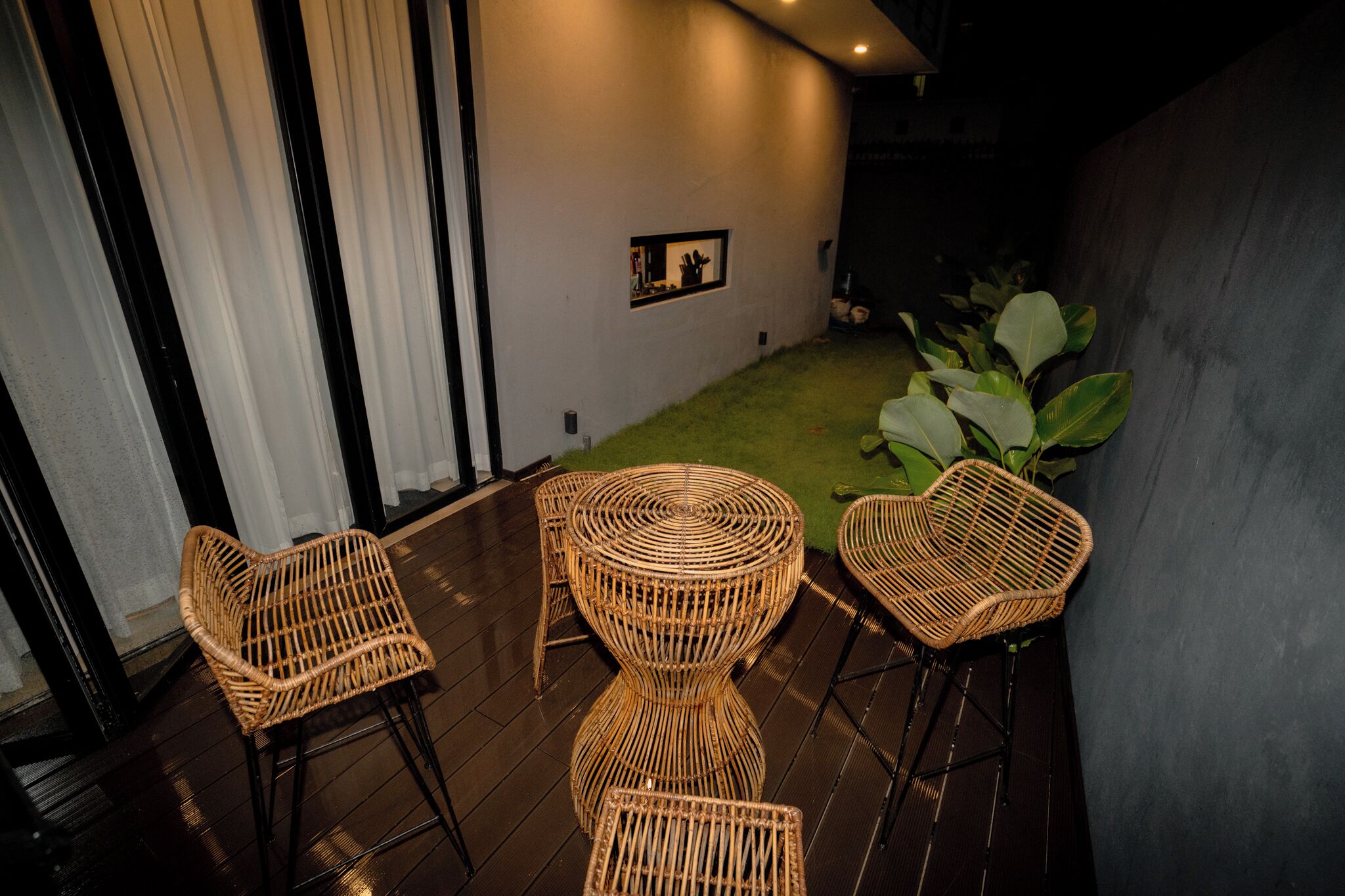 A room with a small grassy area, wicker chairs, and a wall-mounted picture.