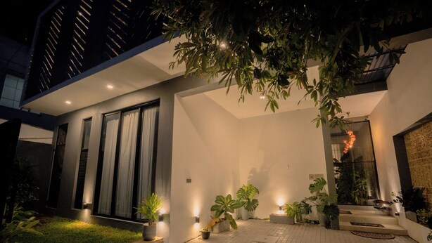 A modern building with a flat roof, large windows, and a well-lit entrance area with potted plants.