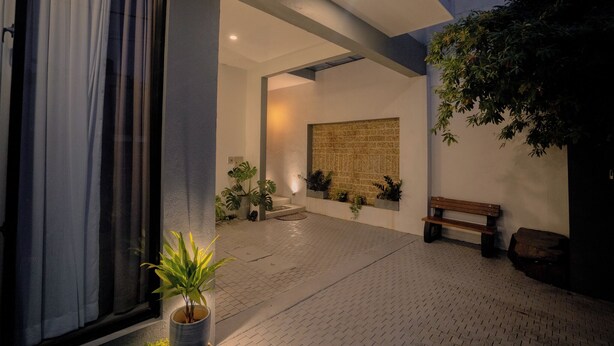 Un espacio al aire libre con un banco, plantas en macetas y una pared con textura.