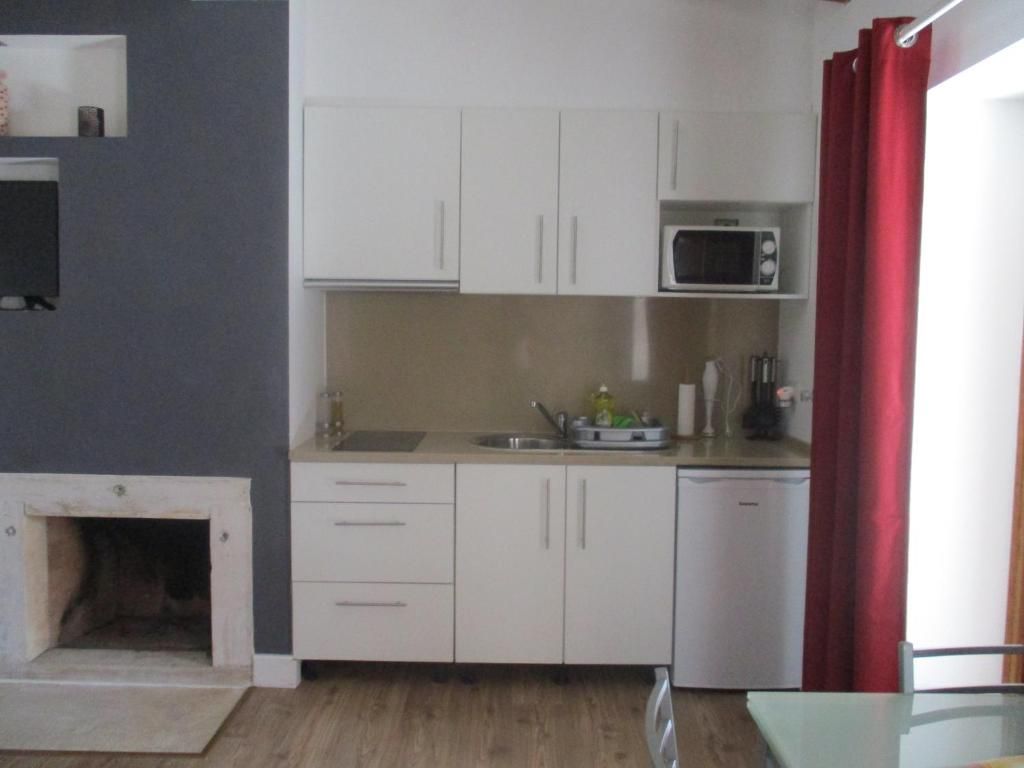 Una cocina compacta con muebles blancos, microondas, fregadero y lavavajillas.