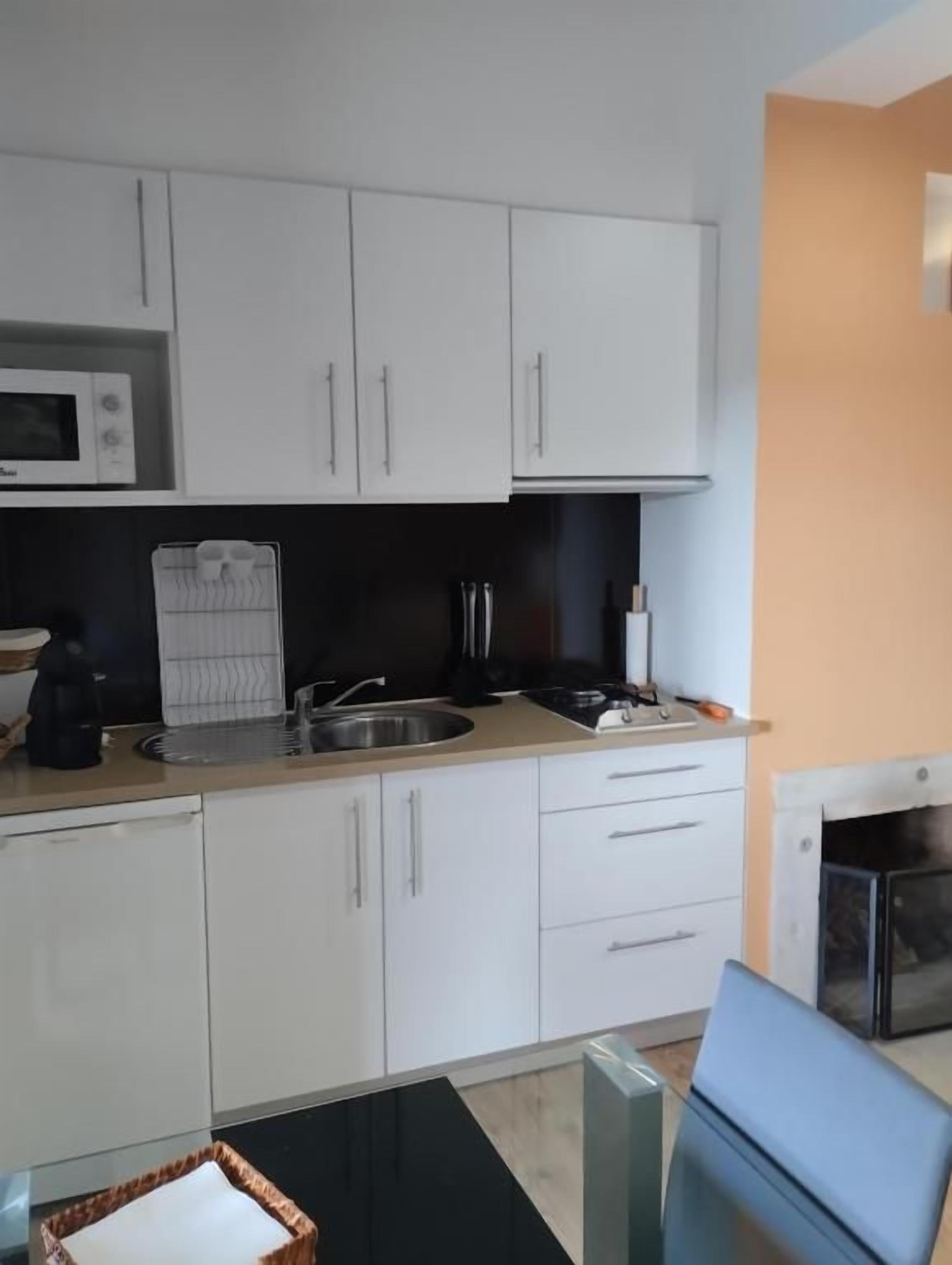 A compact kitchen with white cabinets, a microwave, a sink, and a stove.