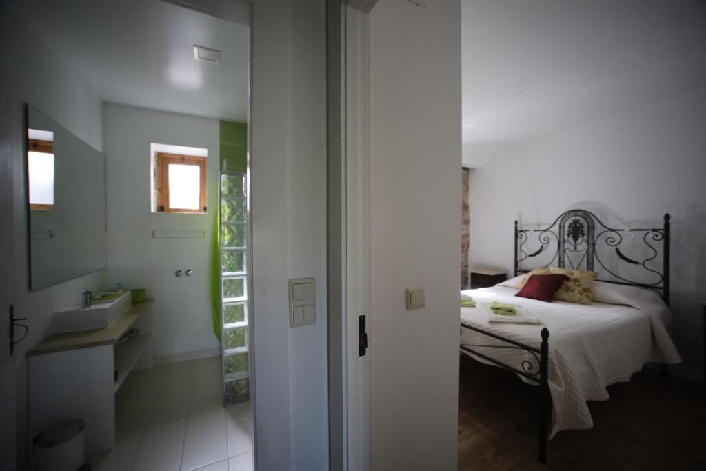 Un dormitorio con cama, mesita de noche y ventana.
