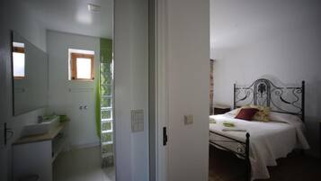 Un dormitorio con cama, mesita de noche y ventana.
