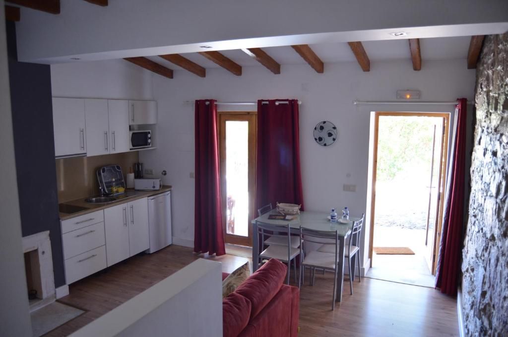 Cozinha compacta com armários brancos, micro-ondas e área de jantar com mesa e cadeiras.