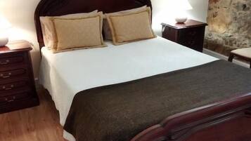 A bedroom with a wooden bed, a nightstand, and a stone wall.