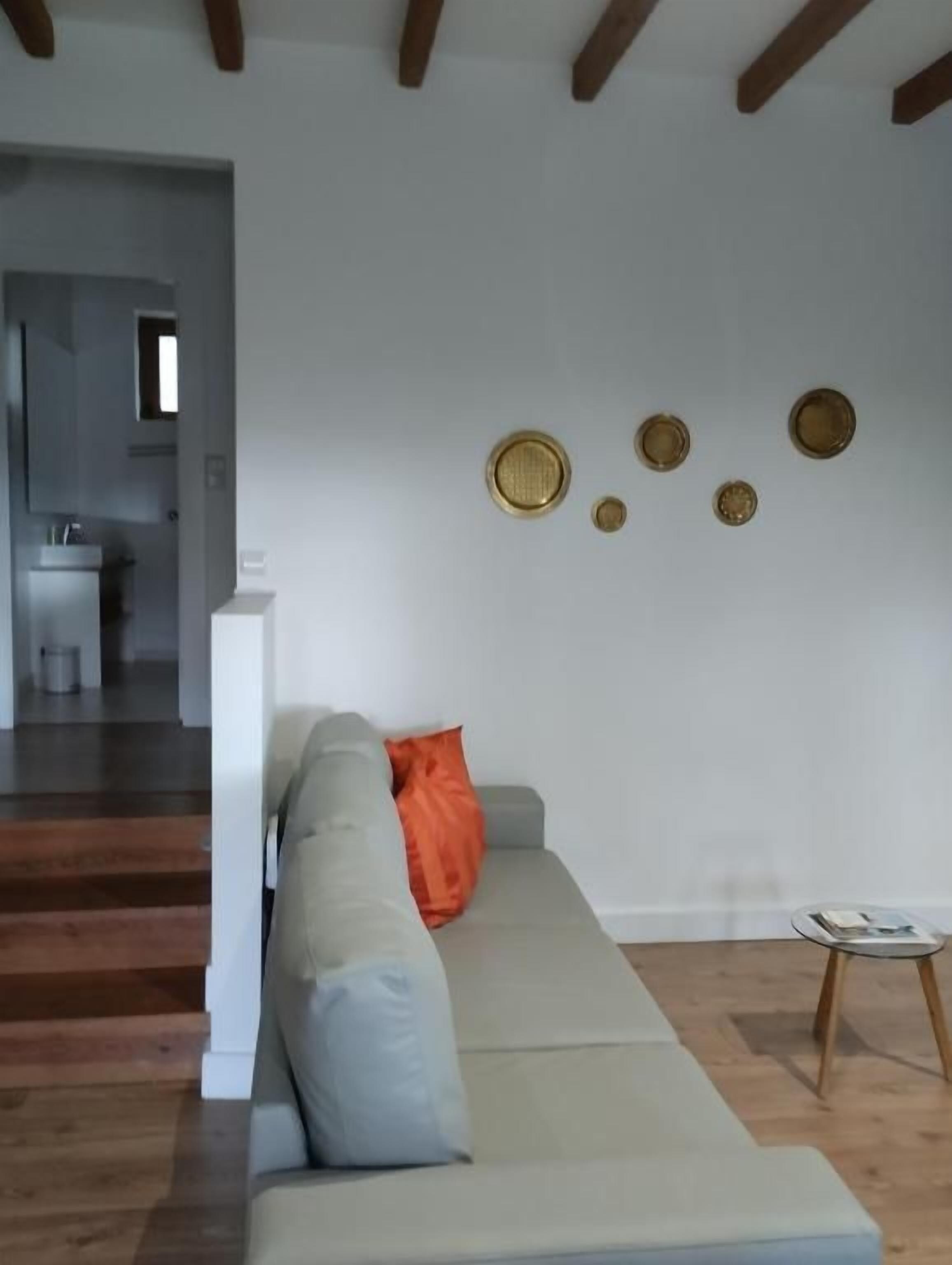 A living room with a sofa, a small table, and a staircase leading to another room.