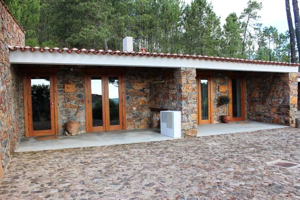Un edificio de piedra con tejado de tejas, puertas de madera y un patio empedrado.