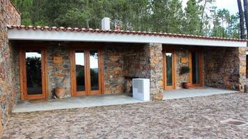 Un edificio de piedra con tejado de tejas, puertas de madera y un patio empedrado.
